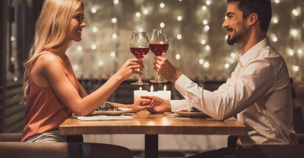 Ein Pärchen stößt mit Rotwein auf ein feierliches Abendessen an.