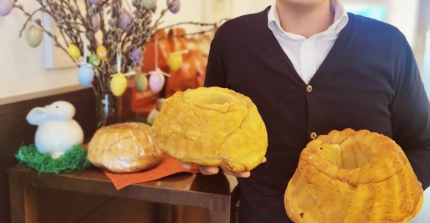 Bäckermeister Taumberger mit zwei Osterreindlingen in den Händen vor einem osterlich dekorierten Tisch