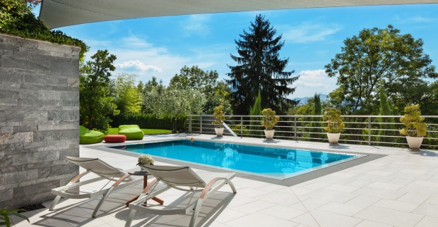 Ein Swimmingpool auf einer Steinterrasse mit Blick auf einen Wald