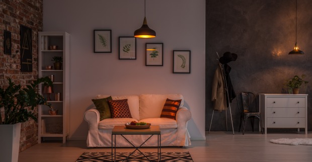 Ein modern gestaltetes Wohnzimmer, das von nur einer schwachen Deckenlampe bescheiden ausgeleuchtet wird