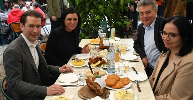 (v.l.) Bundeskanzler Sebastian Kurz (ÖVP), Landwirtschaftsministerin Elisabeth Köstinger (ÖVP), Vizekanzler Werner Kogler (Grüne) und Staatssekretärin Andrea Mayer (Grüne) sizen im Schweizerhaus an einem Tisch mit Stelze, Beilagen und Mineralwasser.
