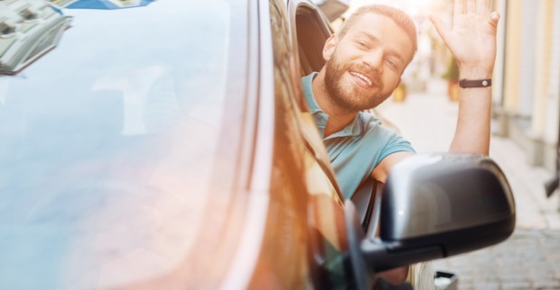 Mann winkt aus dem Auto