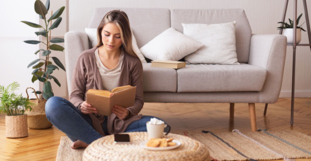 Frau beim Lesen im Wohnzimmer | Credit: iStock.com/Prostock-Studio