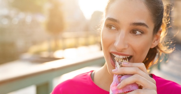 Frau beim Essen eines Müsliriegels | Credit: iStock.com/Ridofranz
