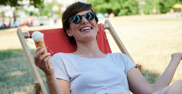 Pamela Rendi-Wagner liegt lachend in einem Liegenstuhl. Sie hat eine Sonnebrille auf und ein Eis in der Hand.