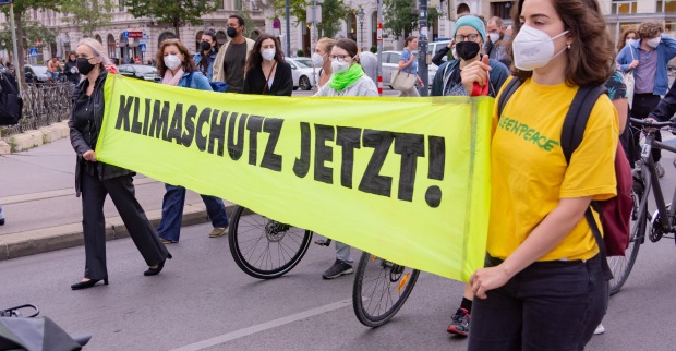Eine Straßendemo, Teilnehmer halten ein Transparent Klimaschutz jetzt!