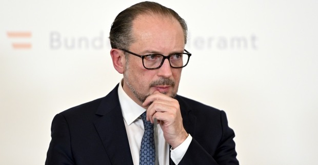 Bundeskanzler Alexander Schallenberg im Halbporträt vor der Pressewand des Bundeskanzleramts. Er hat die Hand an das Kinn gelegt und wirkt nachdenklich.