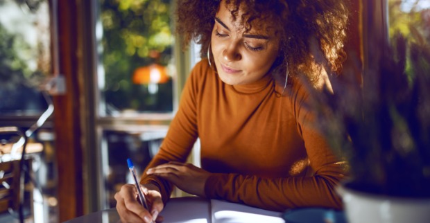 Junge Studentin macht sich Notizen | Credit: iStock.com/dusanpetkovic