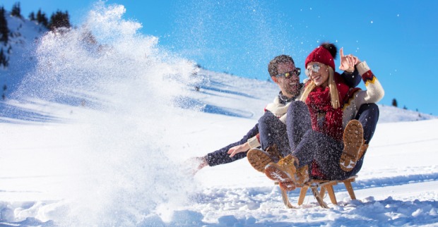 Verliebtes Pärchen bei einer Rodelpartie in den Bergen | Credit: iStock.com/FS-Stock
