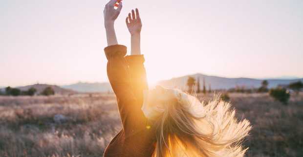 Frau streckt sich im Sonnenaufgang durch und ihre Arme dem Himmel entgegen | Credit: iStock.com/Primorac91