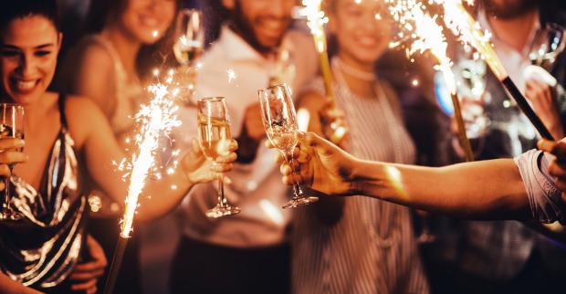 Menschen stoßen mit Champagner an und halten Wunderkerzen in Händen