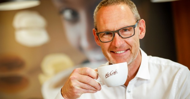 Rudolf Ringhofer führt eine Kaffeetasse mit McCafé-Logo zu seinem Mund