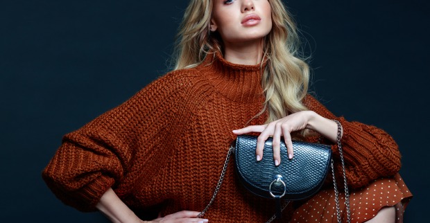 Frau in einem braunen Pullover mit schwarzer Tasche