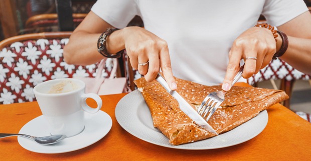 Junge Frau beim Verspeisen einer Crêpe | Credit: iStock.com/frantic00