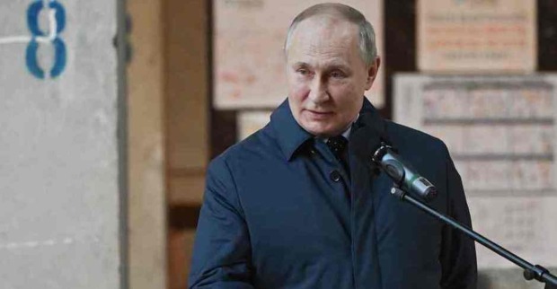 Putin in blauem Mantel, davor ein Mikrofonständer