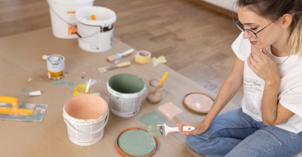Frau sitzt mit Malutensilien am Boden | Credit: iStock.com/SolisImages