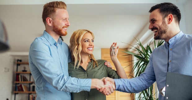 Makler schüttelt einem Mieter und seiner Freundin die Hand | Credit: iStock.com/bernardbodo