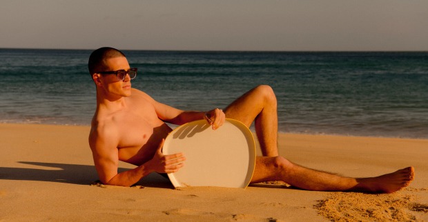 Mann liegt mit Sonnenbrille am Strand