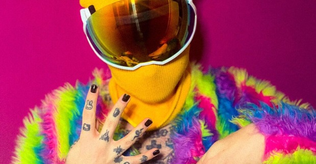Der Influencer Ian Jules in einer regenbogenfarbenen Felljacke mit gelber Schimütze und Spiegelvisir