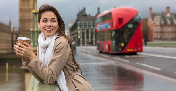Junge Frau mit Coffee-to-go lehnt an einer Brücke nahe dem Big Ben in London | Credit: iStock.com/dmbaker