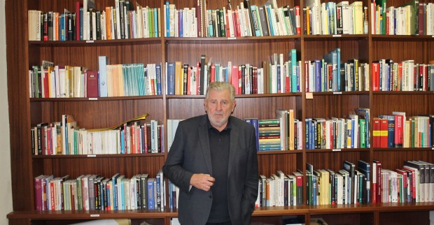 Der Obmann des KHD, Andreas Mölzer, steht vor einem mehrreihigen Bücherregal mit unzähligen Büchern