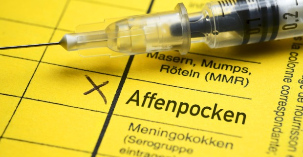 Impfpass Affenpocken und eine Spritze darauf