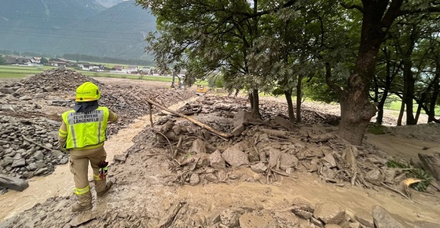 Eine Mure ist abgegangen. Ein Feuerwehrmann steht im Schlamm