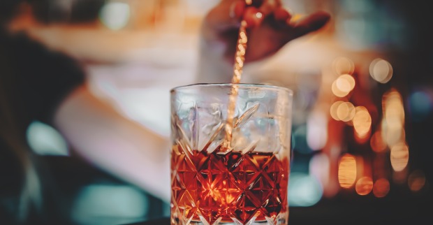 Glas mit Rührstäbchen und rotem Cocktail Negroni
