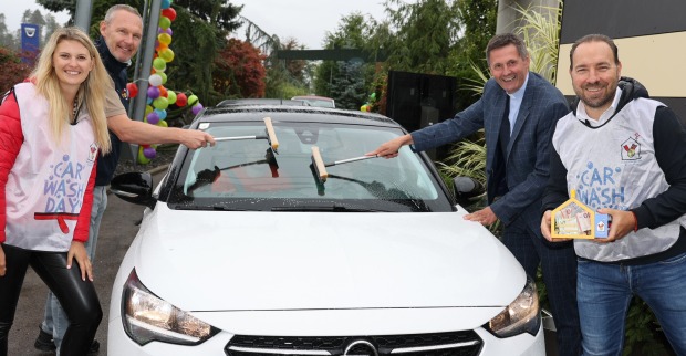 Vier Personen putzen die Scheibe eines Autos