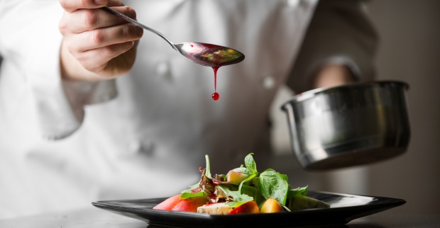 Ein Koch veredelt eine Mahlzeit mit einer Soße