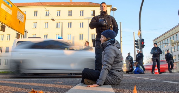 Junge Frau auf Fahrbahn sitzend, Polizist steht dahinter