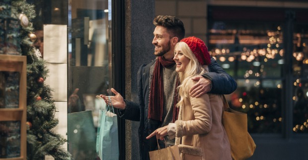 Ein junges Paar, das vor einem weihnachtlich geschmückten Schaufenster steht.