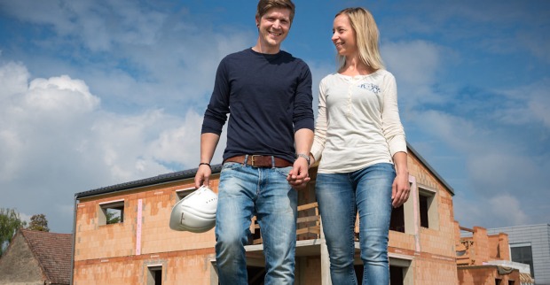 Junges Paar steht vor einem Ziegelrohbau| Credit: Andreas Hafenscher