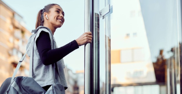 Junge Frau beim Betreten eines Gebäudes | Credit: iStock.com/Drazen Zigic