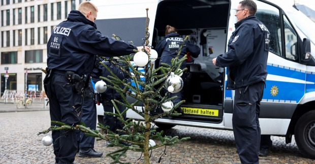 Zwei Polizisten mit Baumspitze vor Einsatzwagen