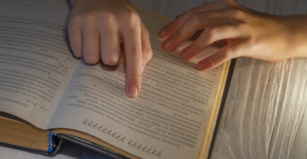 Ein Finger deutet auf eine Seite in einem Wörterbuch, die mit lauter Fragezeichen bedruckt ist