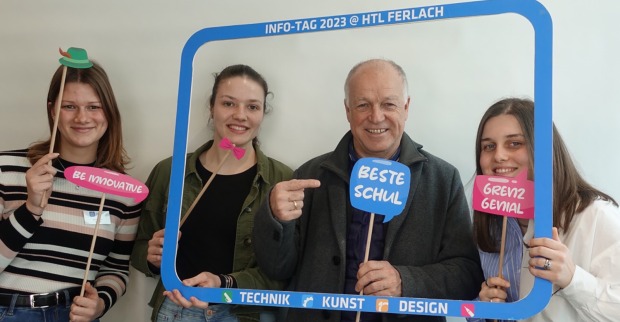 Der Ferlacher Bürgermeister und drei HTL-Schülerinnen, die einen überdimensionalen Bilderrahmen sowie an Sprechblasen erinnernde Werbeschilder in die Höhe halten