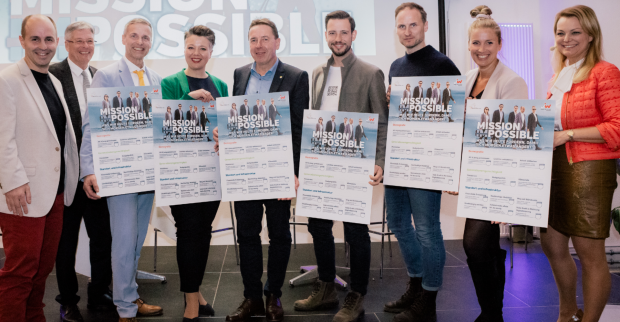Vertreter der JW-Kärnten übergeben den Spitzenkandidaten der Parteien der kommenden Landtagswahl auf einer Diskussionsbühne jeweils eine überdimensionierte Forderungsliste