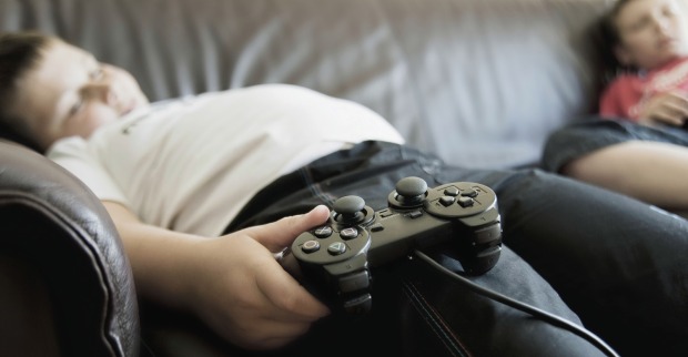 Dickes Kind liegt mit einem Controller auf dem Sofa