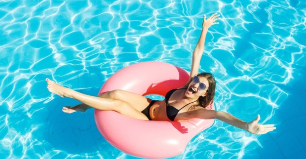Fröhliche junge Frau im Swimming Pool | Credit: iStock.com/Mykola Sosiukin