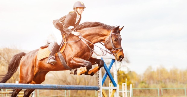 Frau springt mit Pferd über ein Hindernis | Credit: iStock.com/sergio_kumer