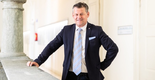 Bürgermeister Scheider, in Anzung und mit einer Krawatte, hinter einer Balustrade im Klagenfurter Rathaus