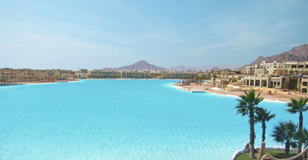 Riesiger hellblauer Pool, an deren Ufer sich im Bau befindliche Hotels reihen