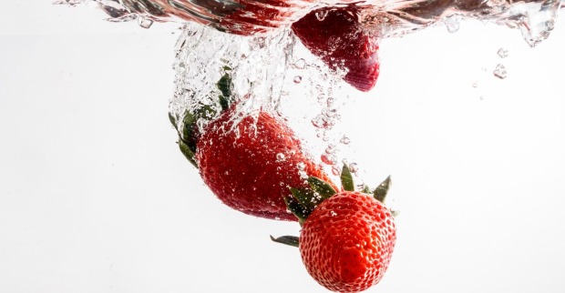 Erdbeeren fallen in Wasser und sprudeln