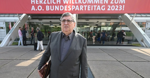 Berthold Felber mit Aktentasche vor dem Eingang des Linzer Designcenters. Über dem Eingang ist ein Transparent mit dem Wortlaut "Herzlich willkommen zum A.O. Bundesparteitag 2023!