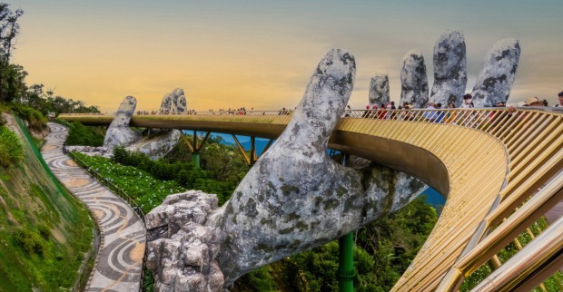Zwei steinerne Hände tragen eine goldene Brücke in Vietnam