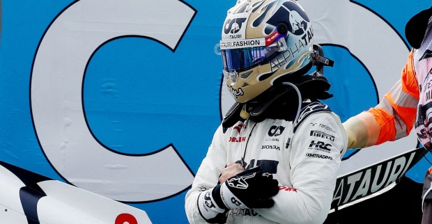 Ricciardo mit Helm und in Rennmontur neben der Strecke. Er hat einen Handschuh ausgezogen und hält sich die linke Hand.