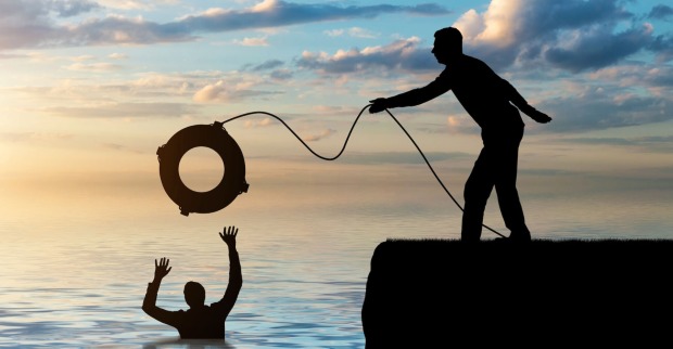 Shilouetten von ertrinkendem und Retter auf dem Kai, der Rettungsring wirft