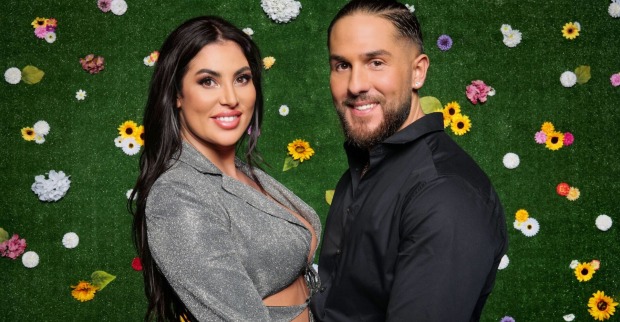 Ricarda und Maurice vom Sommerhaus der Stars vor einer Wand mit Blumen.