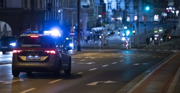Ein Polizeiauto fährt mit Blaulicht nachts über die Straße.